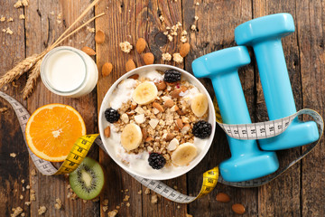 muesli with fruits and yogurt, meter and dumbbell, diet food concept