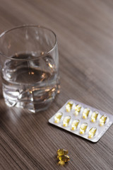pills and glass of water on white background