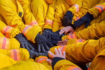 Firefighters team in uniform. Members of the fireman clash their hands to show team work as strong...