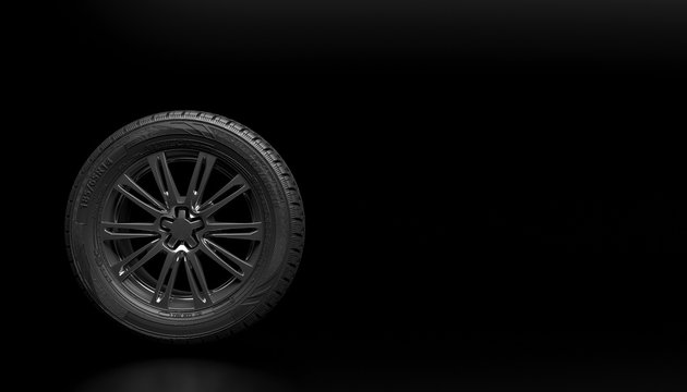 Single new car wheel isolated on a black background. Mock up for advertising car service or auto maintenance. Copy space for text or logo. 3D rendering.