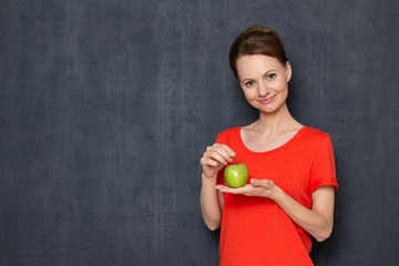 Portrait of happy woman smiling and holding green apple in hands