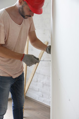 Man drilling screws into plasterboard with a screwdriver, home improvement concept	