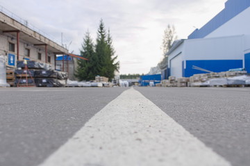 Fototapeta na wymiar Road marking line on asphalt in the territory of an industrial facility in the summer. Ground level view