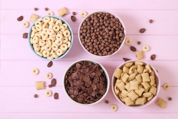 Different types of breakfast cereals on a colored background top view.