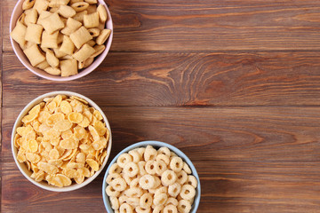 Different types of breakfast cereals on a colored background top view.
