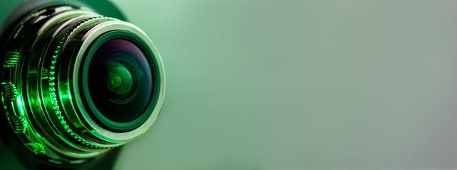 Banner. The camera lens and light green. Side view of the lens of camera on green background. Camera Lens close Up. Optics