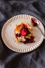 fresh made plum crumble on white plate