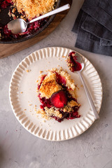 fresh made plum crumble on white plate. top view