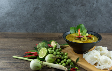 Green curry (Kaeng kheiyw hwan) with Thai food for steamed rice or rice noodles. chicken green curry is thai food very popular on dark wooden background. top view