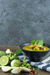 Green curry (Kaeng kheiyw hwan) with Thai food for steamed rice or rice noodles. chicken green curry is thai food very popular on dark wooden background. top view