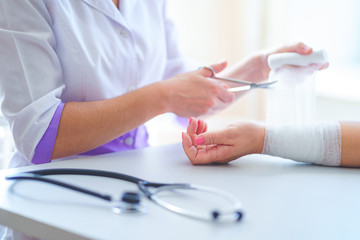 General practitioner bandages wrist of patient in hospital