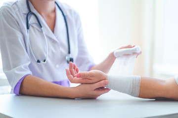 Doctor is bandaging wrist of patient in hospital