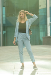 Fototapeta premium Outdoors lifestyle fashion portrait of happy stunning blonde girl. Beautiful smile. Walking to the city street. Long light hair. Joyful and cheerful woman. Happiness.