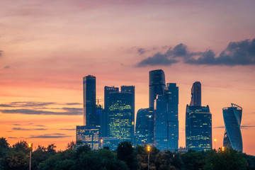 Skyscrapers in Moscow city district against red and orange sunset sky. Evening view.