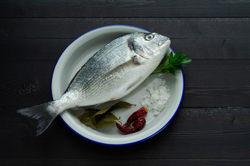 Bream in white plate on black background. Fish in black background. Top view.