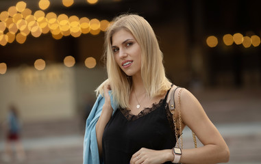 Outdoors lifestyle fashion portrait of happy stunning blonde girl. Beautiful smile. Walking to the city street. Long light hair. Joyful and cheerful woman. Happiness.