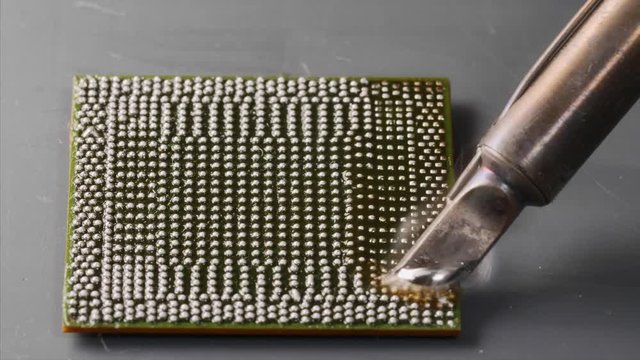 The chipset reballing by soldering iron and rosin by melting under the high temperature with smoke, close-up.