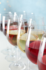 Glasses with wine against light blue background, blurred lights, closeup