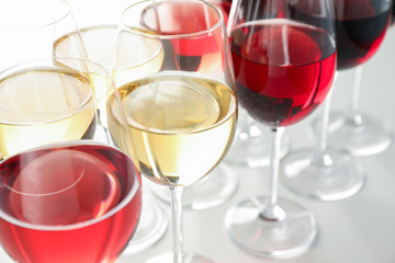 Glasses with different wine on white background, close up