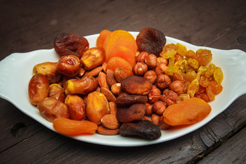 Mixed turkish nuts (walnuts, raisins, dried apricots, almonds, hazelnuts). Assorted nuts and dried fruits in white plate.