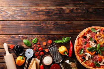 Delicious pizza and ingredients on wooden background, copy space