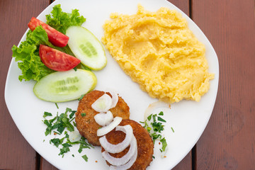 mashed potatoes with cutlet and salad on a white plate close-up