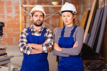 Portrait of two confident workers in uniform inside brick cottage