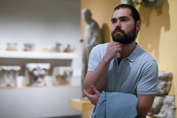 Man looking at stone architectural elements in historical museum hall