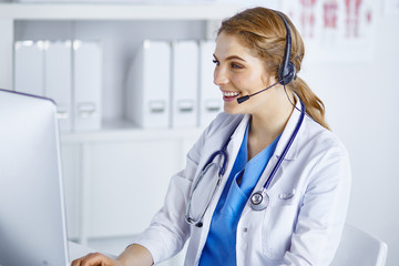 Portrait of a happy smiling young doctor in headset in office