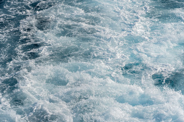 Fototapeta na wymiar Splashing drops of blue sea water during the movement of the ship.