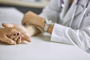 Woman doctor calms patient and holds hand