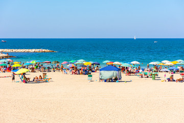 View of a beach with people bathing and sunbathing