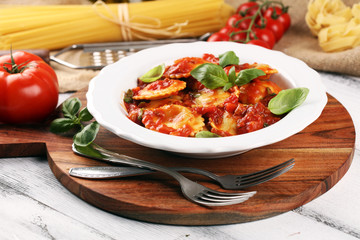 Ravioli with tomato sauce garnished with parmesan cheese and basil on rustic table