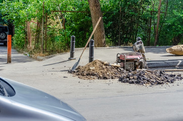 Professional tools for repairing asphalt road pit: shovel, hammer on the background of the city. Overhaul of the main street of the city, road construction; Tbilisi