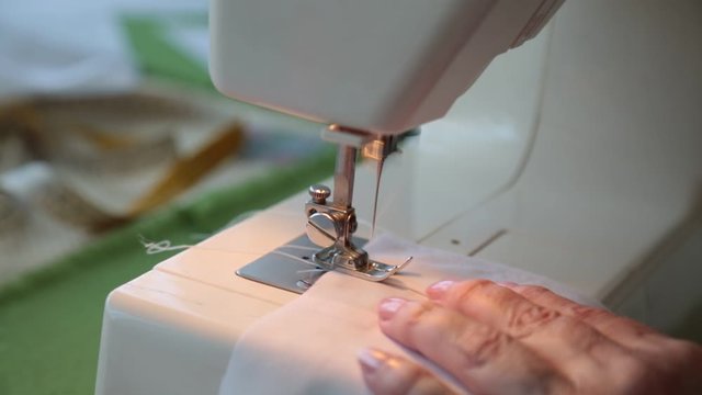 Stitching on electric sewing machine of white material. Technology Household hobby