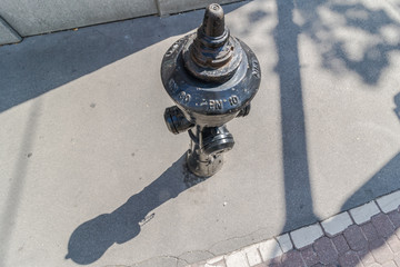 closeup of old weathered fire hydrant on street. black fire hydrant with shadow. Top view. help for...