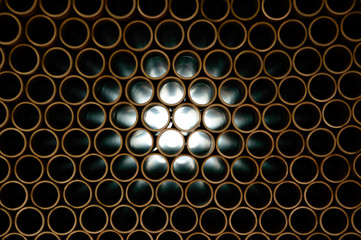 Copper pipes, light penetrates through numerous openings.