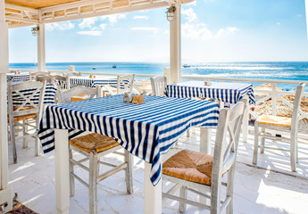 Beautiful view over traditional Greek tavern tables, blue sea and sky on the background. Food trip...