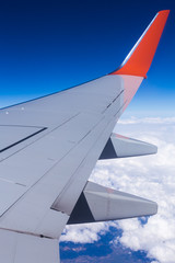 Aerial view of cloud blue sky and plane wing view through the airplane window.