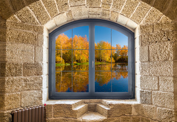 Fragment of a stone wall with a window. Autumn landscape outside the window