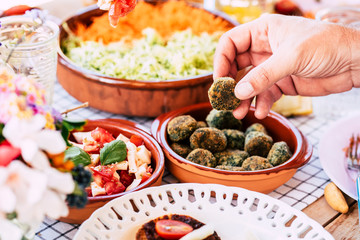 Close up of man taking polpetta in vegetarian food table - concept of market and catering restaurant for party or event