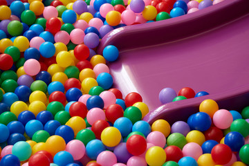 Dry children's pool with plastic slider and colorful balls.