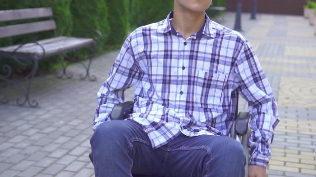 Portrait young asian man disabled in wheelchair rides in park slow mo