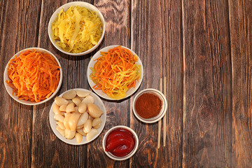 Korean side dishes for a barbecue dinner - kimchi and various kinds of vegetables, a set of fermented foods useful for intestinal health - top view of glass bowls on a wooden background,