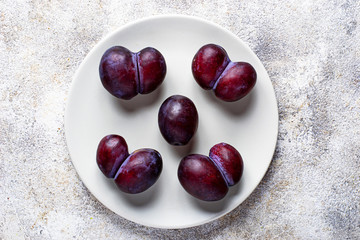 Ugly and normal plums. Abnormal organic fruit