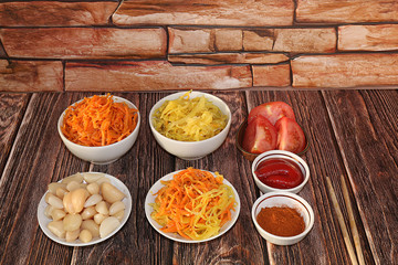 Chinese side dishes for a barbecue dinner - kimchi and various kinds of vegetables, a set of fermented foods useful for intestinal health - top view of glass bowls on a wooden background,