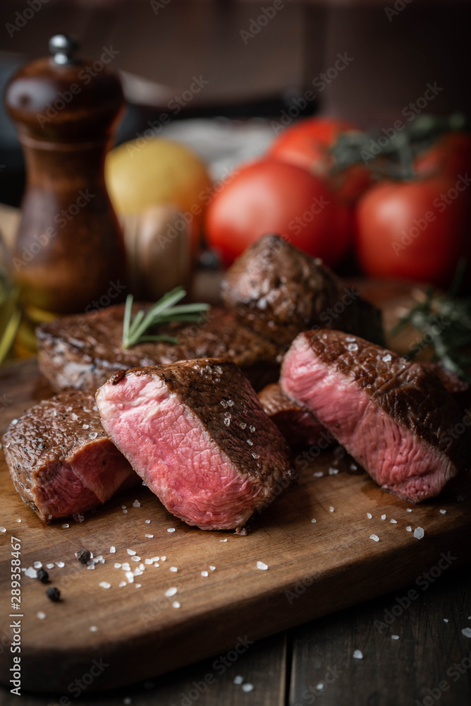 Wall mural rare grilled tenderloin beef steak on cutting board with vegetables