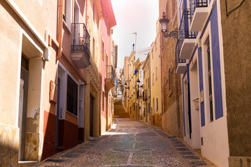 Fototapeta premium The cozy street of the old European city of Relleu is paved with cobblestones in the form of a picture. Mediterranean architecture in Spain.