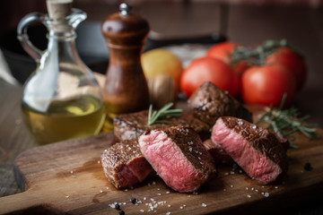 rare grilled tenderloin beef steak on cutting board with vegetables