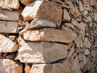 The corner of old stone wall close up, texture background, natural color on the sunny day.